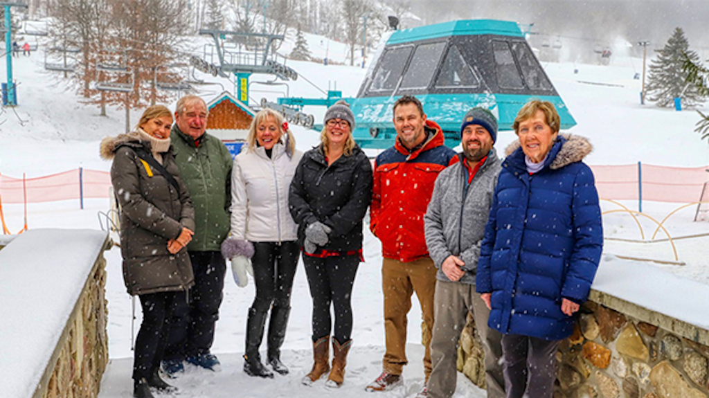 Seven Holiday Valley Realty Agents pose for a picture on a snowy, winter day.